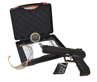 A black replica pistol displayed next to its open black foam-lined carrying case, with safety glasses, a medallion, and papers inside the case.